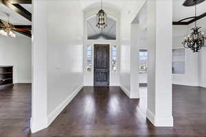 Foyer entrance with a chandelier, vaulted ceiling, dark wood finished floors, and ceiling fan