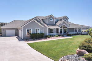 View of front of house featuring a front yard, covered porch, an attached garage, concrete driveway, and a tile roof