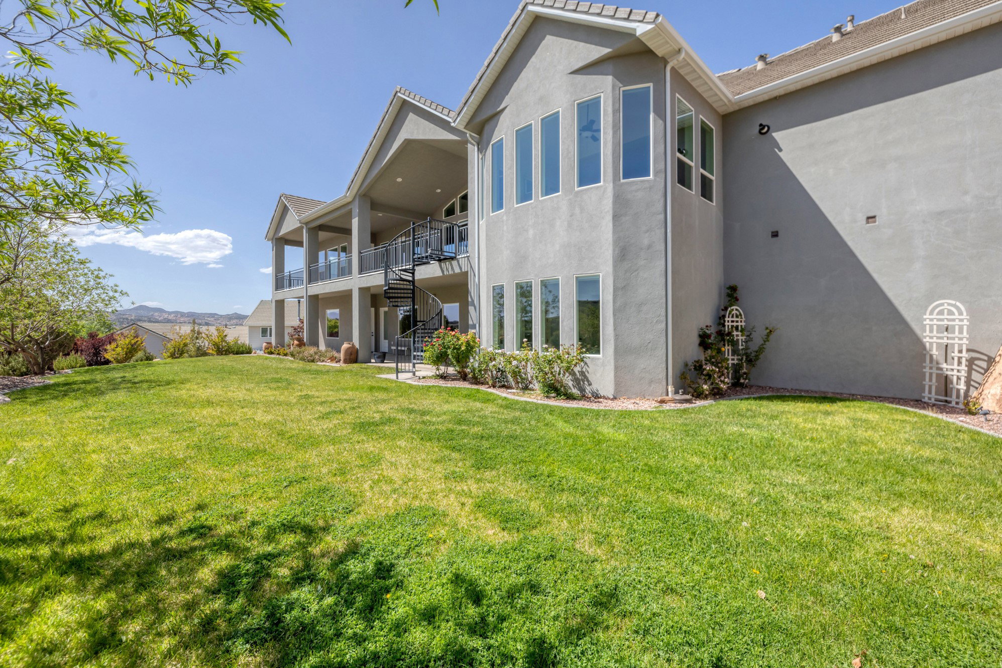Rear view of house with a yard, stucco siding, a patio, and a mountain view