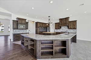 Kitchen featuring open shelves, backsplash, dark wood finish cabinets, and a chandelier