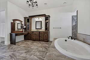 Bathroom featuring vanity, a jetted tub, and suspended lighting