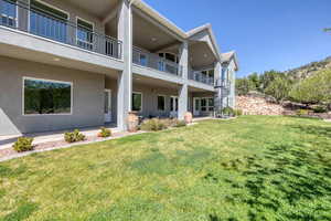 Back of house featuring stucco siding, a patio, and a yard