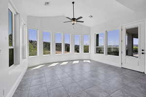 Unfurnished sunroom with lofted ceiling, tile patterned flooring, and healthy amount of natural light