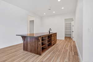 Bar area with wood finish floors, open shelves, recessed lighting, and dark stone countertops