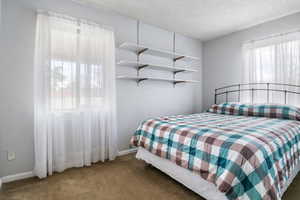 Carpeted bedroom with a textured ceiling and baseboards