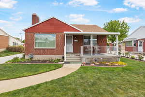 Bungalow-style home featuring a porch, a front lawn, a chimney, brick siding, and a shingled roof