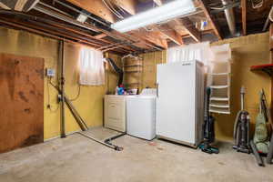 Unfinished below grade area featuring freestanding refrigerator and washer and dryer