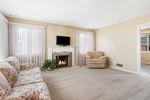 Living room featuring light carpet and a lit fireplace