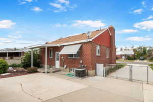 Back of property featuring a gate, a chimney, a patio area, and brick siding