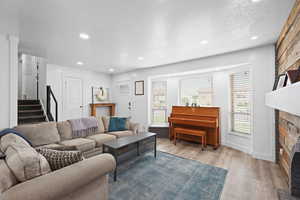 Bright living room with a beautiful bay window, updated flooring, and natural light highlighting the warm fireplace feature wall.