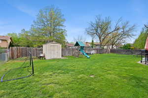 Fenced backyard with a storage shed and a playground