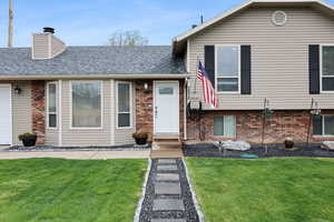 Split level home featuring a front lawn, brick siding, and roof with shingles