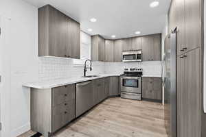 Updated kitchen with modern cabinetry, tile backsplash, and stainless steel appliances with plenty of storage.