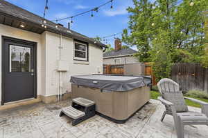 Fenced backyard featuring a patio area, a hot tub, and an outdoor structure