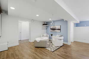 Sitting room with light wood finished floors, a wainscoted wall, and recessed lighting