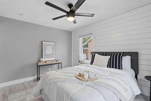 Bedroom with wood finished floors, a ceiling fan, and wooden walls