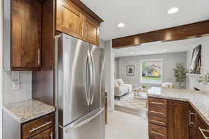 Kitchen with freestanding refrigerator, light stone countertops, a fireplace, recessed lighting, and open floor plan