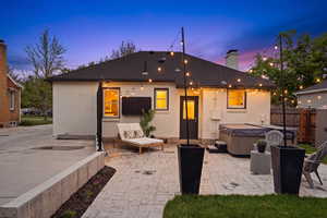 Back of house featuring a patio area, brick siding, a chimney, and a hot tub