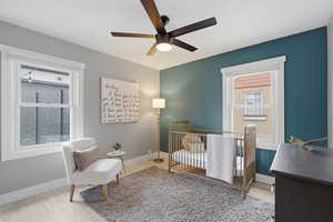 Bedroom featuring a crib, light wood-type flooring, and a ceiling fan