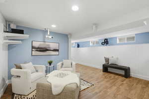 Sitting room with wood finished floors, a wainscoted wall, and recessed lighting