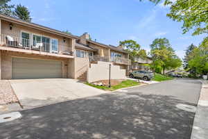View of front of house featuring brick siding, concrete driveway, a balcony, and a garage