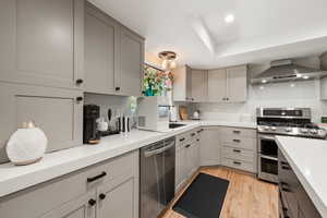 Kitchen featuring gray cabinets, stainless steel appliances, light wood finished floors, recessed lighting, and light stone countertops