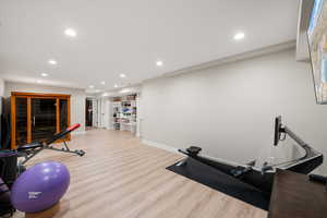 Exercise area with a relaxing sauna, light wood-style floors, and recessed lighting