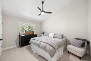 Bedroom featuring vaulted ceiling, a ceiling fan, and light colored carpet