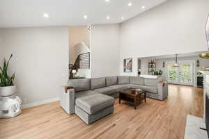 Living room with light wood-type flooring, recessed lighting, a high ceiling, and a fireplace