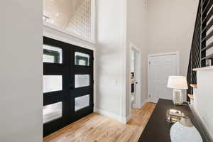 Foyer with light wood-type flooring, a high ceiling, and french doors