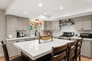 Kitchen with a breakfast bar, gray cabinets, light wood-style flooring, stainless steel appliances, and recessed lighting