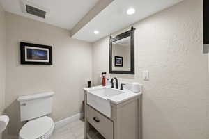 Bathroom featuring a textured wall, vanity, and recessed lighting