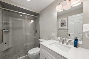 Bathroom featuring vanity, a stall shower, and tile walls