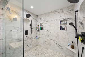 Bathroom with a marble finish shower and recessed lighting