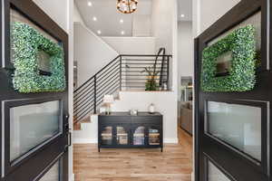 Foyer with light wood finished floors, a chandelier, and a high ceiling