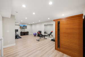 Exercise room featuring a sauna, light wood-type flooring, and recessed lighting