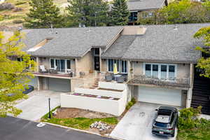 View of front of property featuring brick siding, roof with shingles, an attached garage, and a balcony