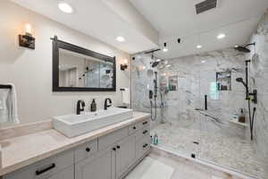 Bathroom featuring vanity, a marble finish shower, and recessed lighting