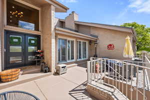 Property entrance with brick siding, a chimney, and a patio
