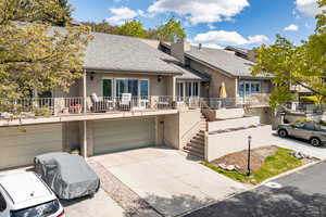 View of front of house with a garage, concrete driveway, roof with shingles, brick siding, and a balcony