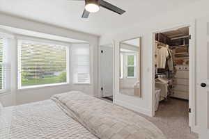 Carpeted bedroom featuring a walk in closet, and ceiling fan