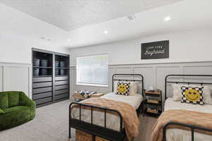Carpeted bedroom with a decorative wall, a wainscoted wall, a textured ceiling, and recessed lighting