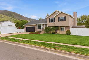 Tri-level home with brick siding, a gate, concrete driveway, and a garage