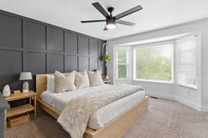 Carpeted bedroom with a decorative wall and a ceiling fan