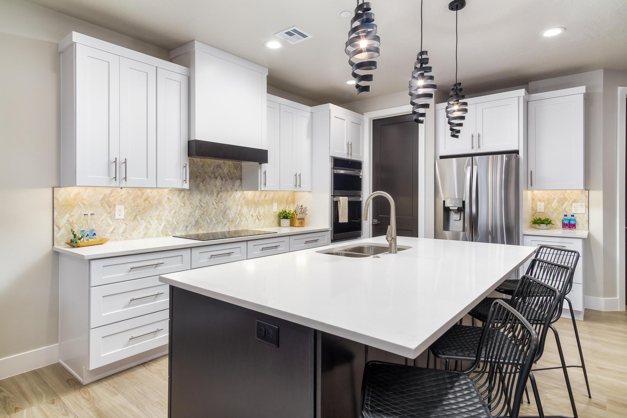 Kitchen featuring a breakfast bar, stainless steel appliances, a kitchen island with sink, light wood-style floors, and two tone cabinets