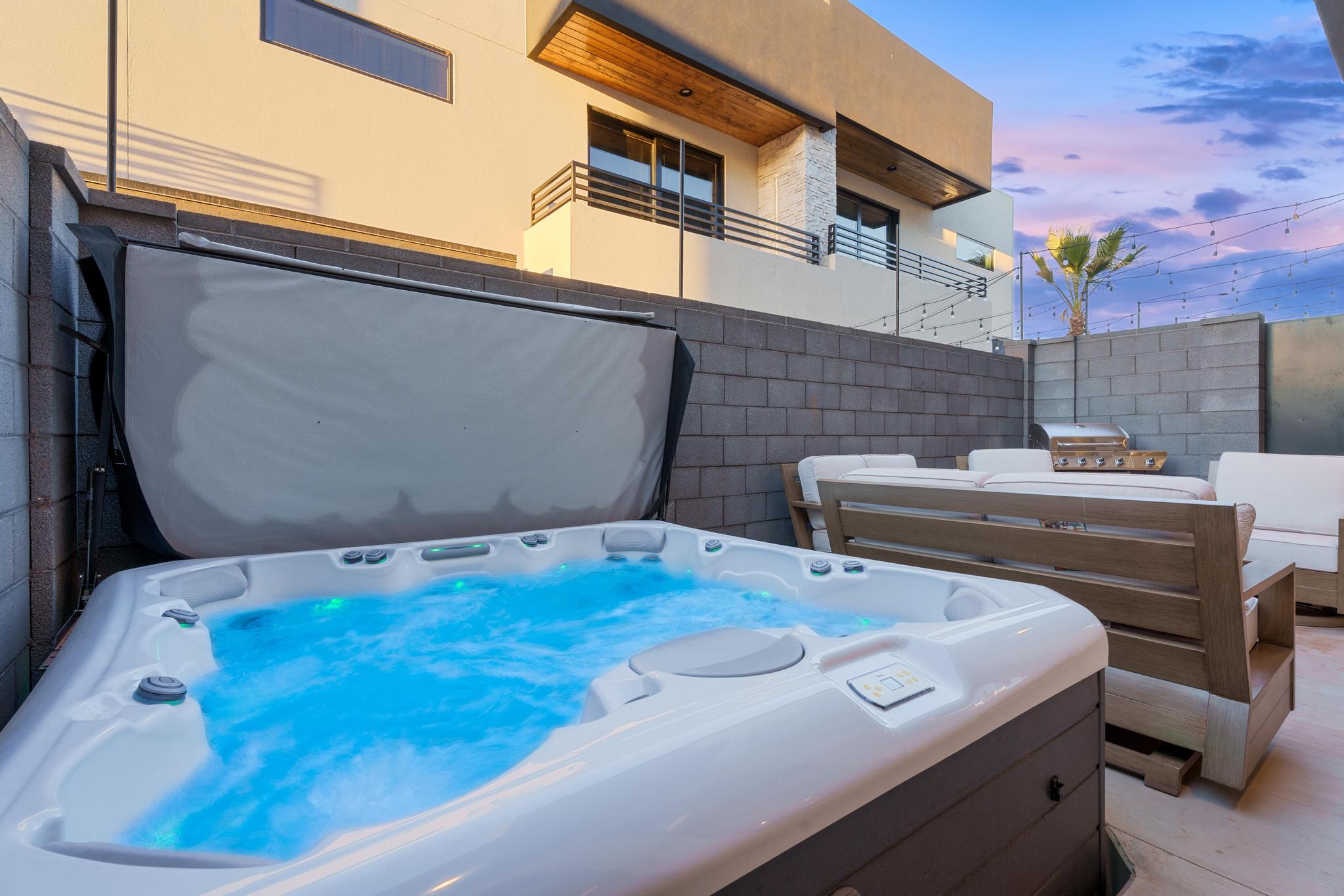 Patio terrace at dusk featuring a hot tub and a balcony