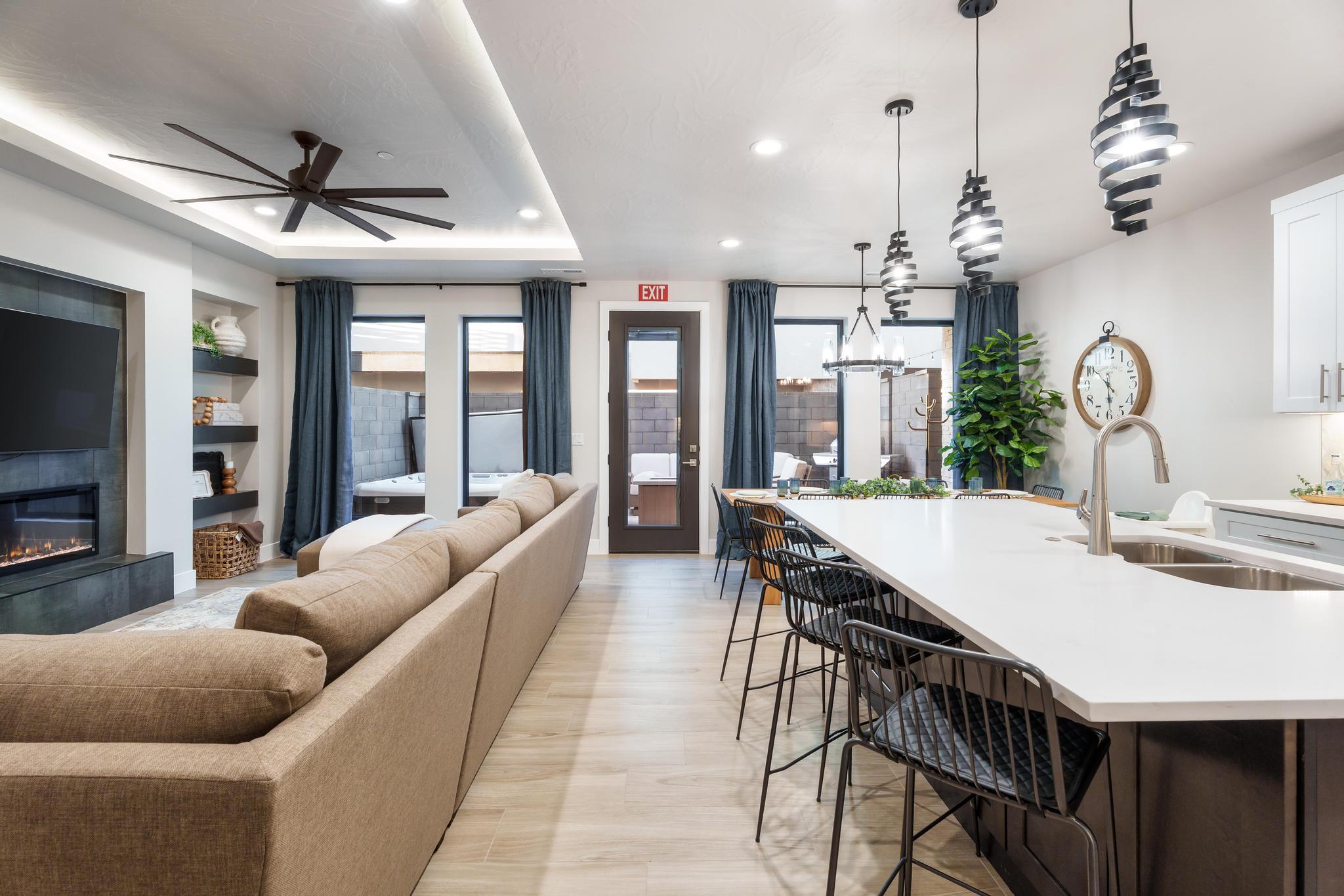 Living room featuring recessed lighting, ceiling fan, a glass covered fireplace, and a tray ceiling