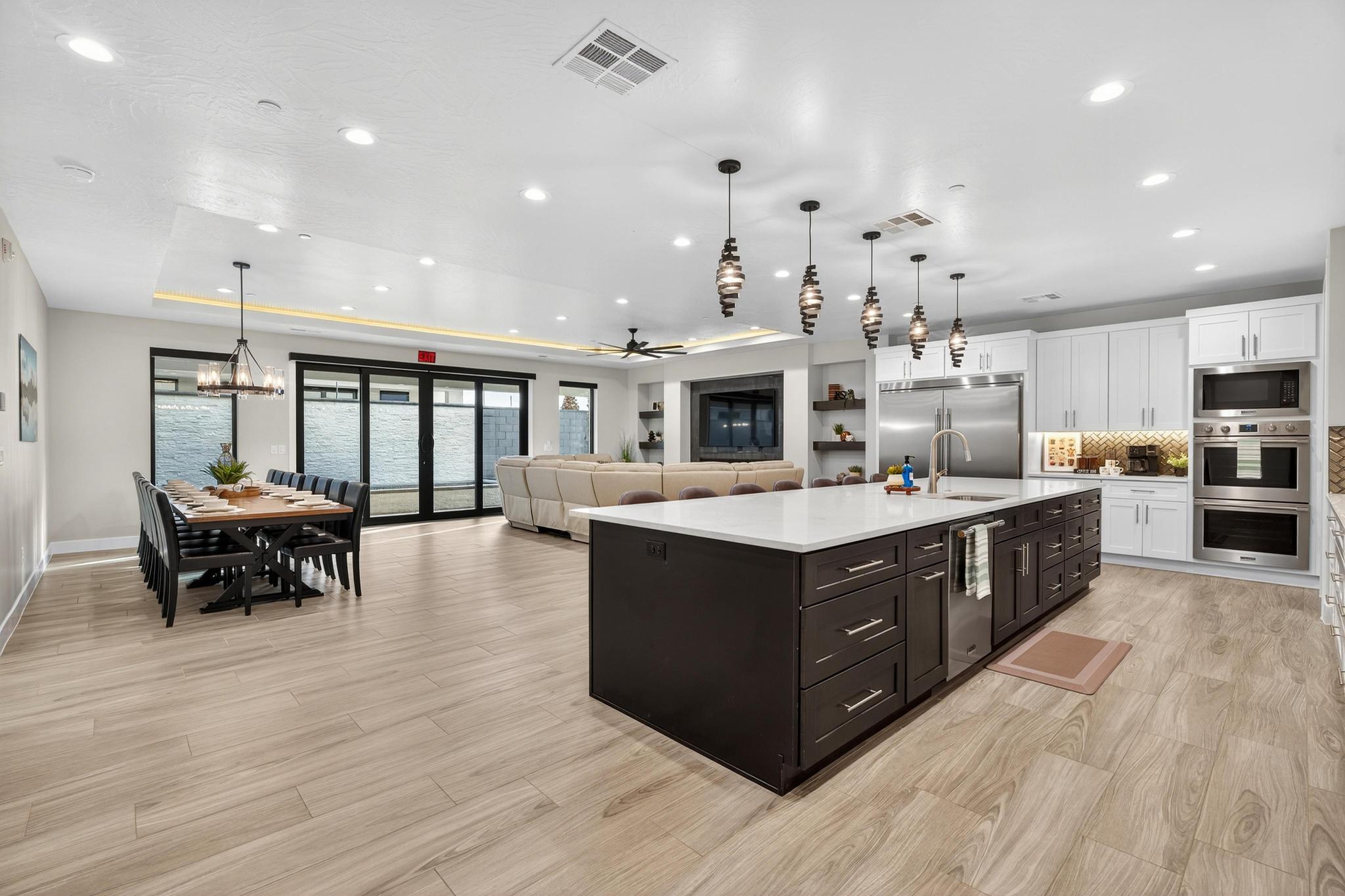 Kitchen featuring ceiling fan, open floor plan, a center island with sink, two tone cabinetry, and built in appliances