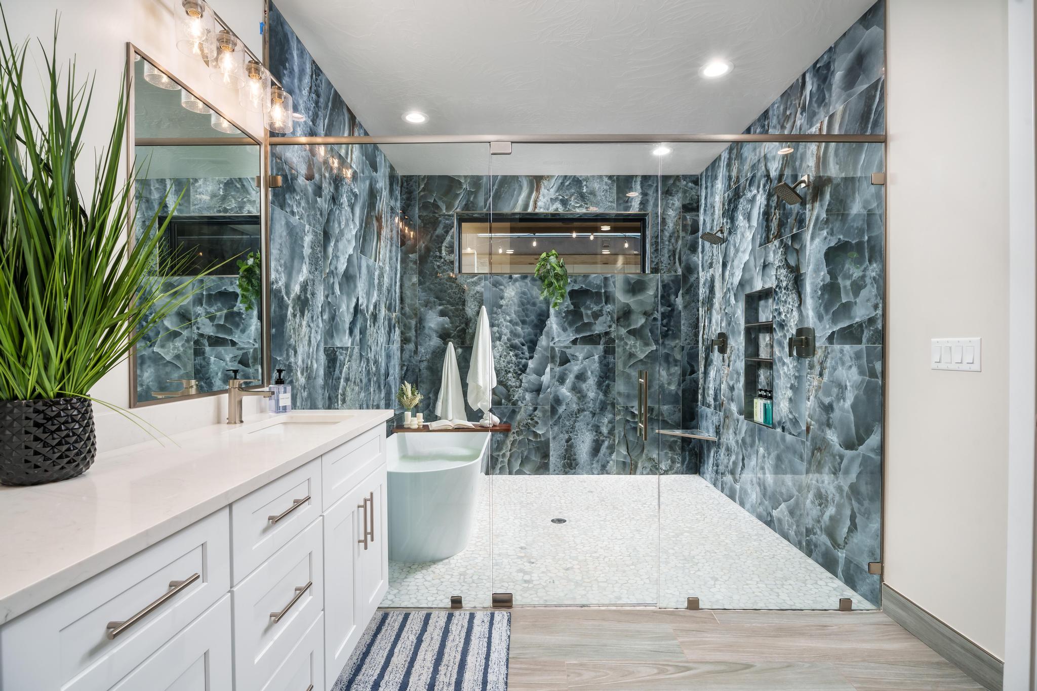 Bathroom with a freestanding tub, a marble finish shower, vanity, tile walls, and recessed lighting