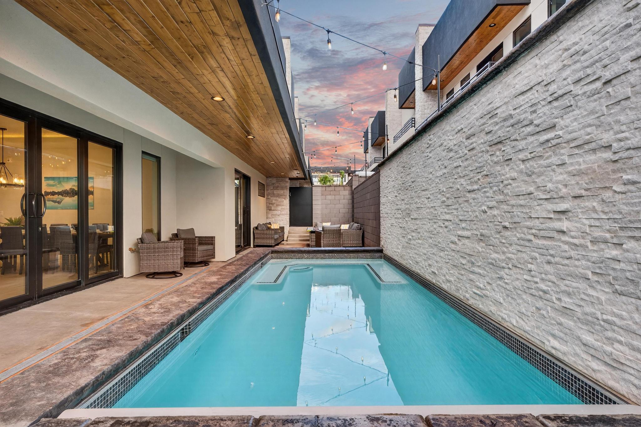 Pool at dusk with a fenced backyard and a patio area